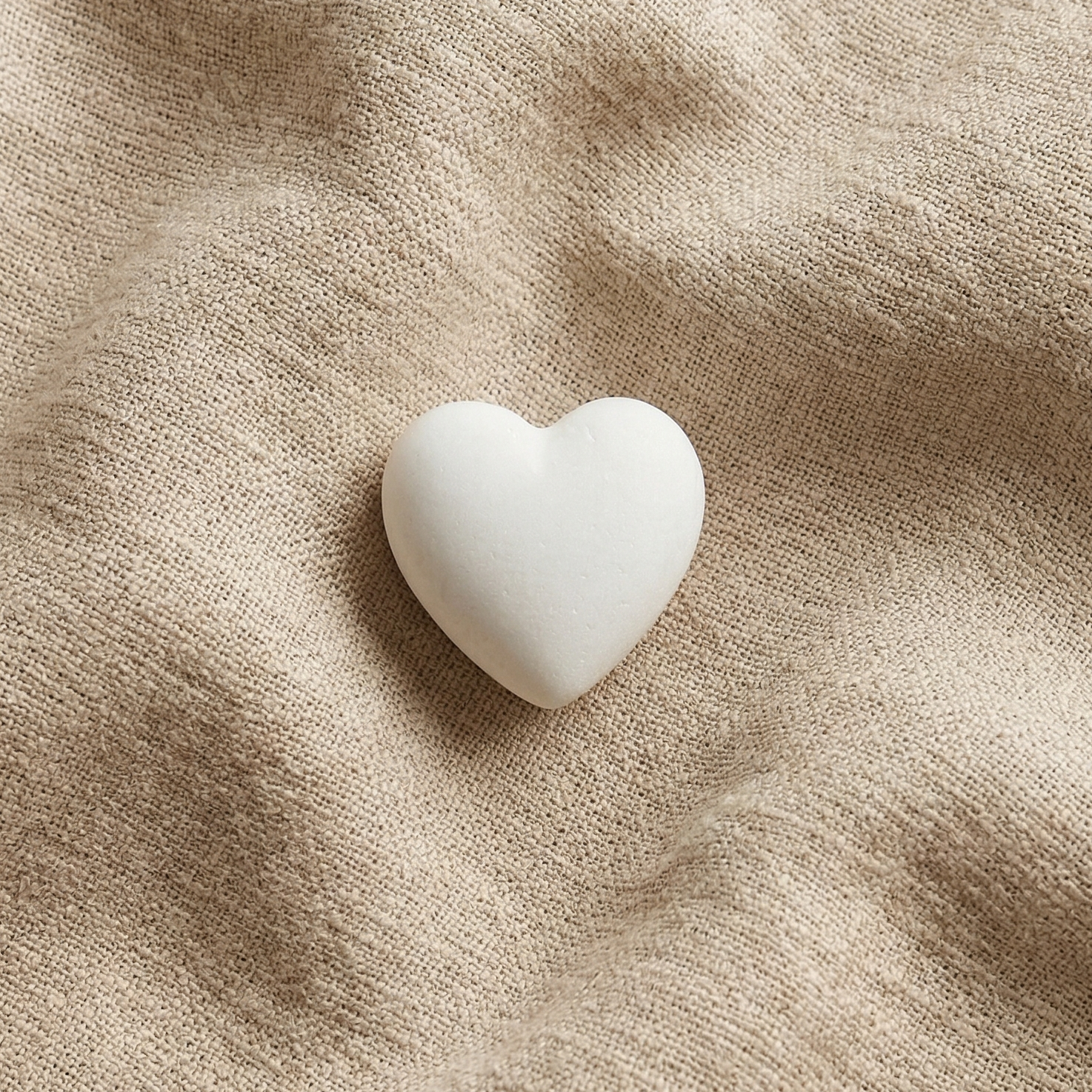Cuore Custode: piccolo cuore bianco levigato appoggiato su tessuto di lino naturale